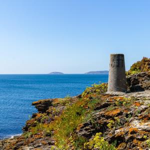 a stone tower on a cliff next to the ocean at Camping Paxariñas in Portonovo