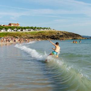 Un uomo che cavalca un'onda su una tavola da surf sulla spiaggia di Camping Paxariñas a Portonovo