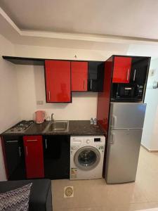 una pequeña cocina con armarios rojos y nevera. en apartment 60m 1bedroom for rent3 en Umm Uthainah