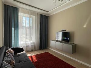 Una sala de estar con un sofá y un televisor de pantalla plana. en Dream City 15, en Astana