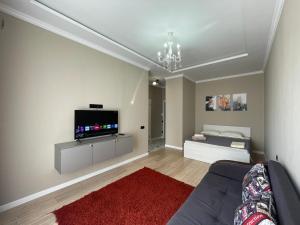 Una sala de estar con un sofá y un televisor en una pared. en Dream City 15, en Astana