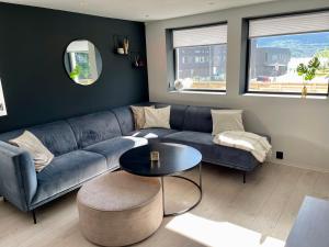 Luxury apartement close to city centre with free parking في ترومسو: غرفة معيشة مع أريكة زرقاء وطاولة