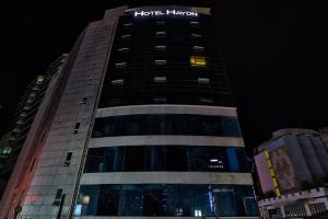 a tall building with a sign on it at night at Hotel Haydn in Busan