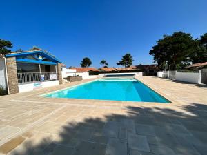 a swimming pool in a yard next to a house at L'évasion des pins - Au coeur de la Nature in Saint-Jean-de-Monts +8 photos