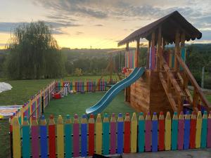 einen Spielplatz mit buntem Zaun und Rutsche in der Unterkunft Casa de vacanta Madalina in Novaci-Străini