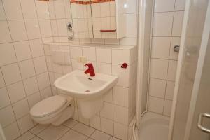 een witte badkamer met een toilet en een wastafel bij Penthousewohnung vor der Promenade in Damp