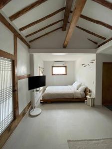 um quarto com uma cama e uma televisão em Bow Hanok House em Gangneung