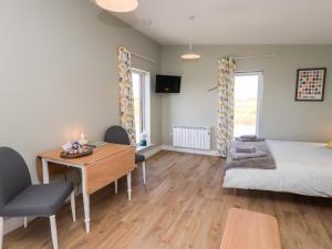 a bedroom with a desk and a bed and a desk and chairs at The Wheelhouse in Carinish