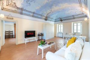 Borgo Alfieri - Elegant suites with stunning view في Magliano Alfieri: غرفة معيشة بها أريكة بيضاء و لوحة على السقف