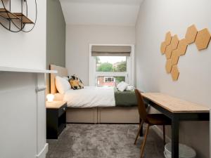 1 dormitorio con cama, mesa y ventana en Pass the Keys Stylish Aigburth Flat Sleeps 12 en Liverpool