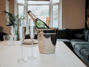 una bottiglia di champagne in un secchio su un tavolo con bicchieri di Pass the Keys Stylish Aigburth Flat Sleeps 12 a Liverpool