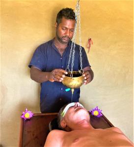 un hombre en una bañera con un hombre acostado en Ayurveda Suwetha Villa, en Bentota