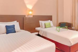 a hotel room with two beds and a laptop on it at Urbanview Hotel Grand Permata In Banjarbaru by RedDoorz in Ulin