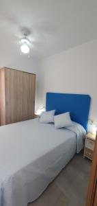 a bedroom with a white bed with a blue headboard at APARTAMENTOS LA PALMERA in Fernán Pérez