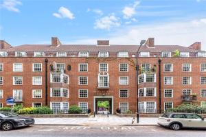 un grande edificio in mattoni rossi con macchine parcheggiate di fronte di Designer Flat in Bethnal Green a Londra