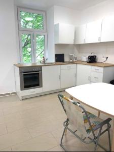 uma cozinha com armários brancos, uma mesa e uma cadeira em Top location single by Bahnhof Meidling em Viena