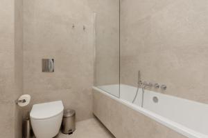 a bathroom with a toilet and a tub and a sink at LUX Apartments Domaniewska with Sauna & Gym by Renters Prestige in Warsaw