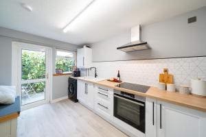 a kitchen with white cabinets and a large window at Heatherwood Cottage in New Scone