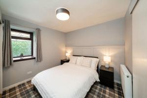 a bedroom with a white bed and two lamps at Heatherwood Cottage in New Scone
