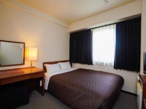 a hotel room with a bed and a desk and a mirror at Plaza Hotel Tenjin in Fukuoka