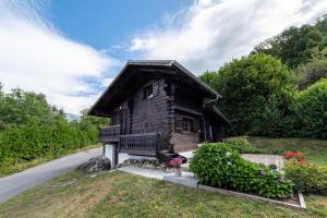 una piccola casa in legno con una panchina accanto a una strada di Chalet du Brey - Avec terrasse et jardin a Saint-Gervais-les-Bains