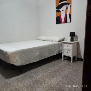 una camera con due letti e un comodino con un quadro di Apto Barcelona C R a Santa Coloma de Gramanet