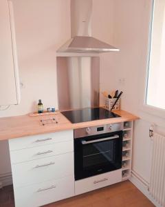een keuken met witte kasten en een fornuis met oven bij Appartement de charme à Digoin in Digoin