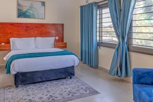 Schlafzimmer mit einem Bett, einem Stuhl und Fenstern in der Unterkunft The Crest Lodge Limited in Lusaka