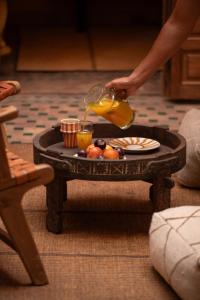 a person pouring a glass of orange juice on a table at Riad Le Petit Bacha in Marrakesh