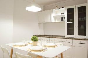 a white kitchen with a white table and chairs at Apartamento Chanteiro I in Ferrol