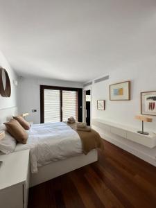 a white bedroom with a large bed and a window at La villa de Berlín en Sevilla in Guillena