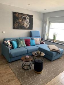 ein blaues Sofa im Wohnzimmer mit zwei Tischen in der Unterkunft NEU! Ferienhaus Schliephake in Schöningen