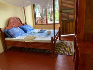 Utende的住宿－Mafia Beach Bungalows sea view，一间卧室配有一张带蓝色枕头的木床。