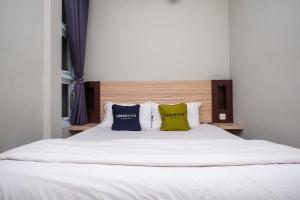 a white bed with three pillows on top of it at Urbanview Stay at H jakal by RedDoorz in Yogyakarta