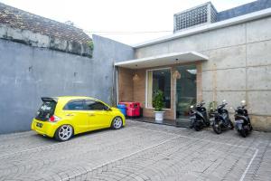 een gele auto geparkeerd voor een gebouw met motorfietsen bij Urbanview Stay at H jakal by RedDoorz in Yogyakarta