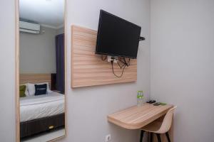 a room with a bed and a tv on a wall at Urbanview Stay at H jakal by RedDoorz in Yogyakarta