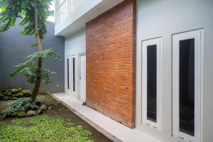 een stenen muur met ramen en een boom ernaast bij Urbanview Stay at H jakal by RedDoorz in Yogyakarta