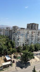 um grande edifício de apartamentos com uma rua em frente em Sunny Apartment in Didi Dighomi em Tbilisi