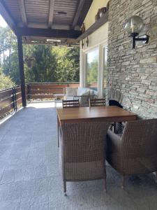 eine Terrasse mit einem Tisch, Stühlen und einer Steinmauer in der Unterkunft Haus Magnolia in Techelsberg am Worthersee