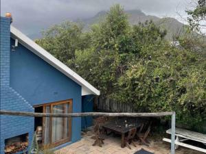 Casa azul con mesa de madera y banco en Kriluki Accommodation en Stellenbosch