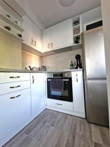 eine Küche mit weißen Schränken und einem Kühlschrank aus Edelstahl in der Unterkunft Apartment ''Simon Green'' in Baltschik
