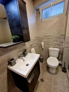 ein Bad mit einem Waschbecken, einem WC und einem Fenster in der Unterkunft Apartment ''Simon Green'' in Baltschik