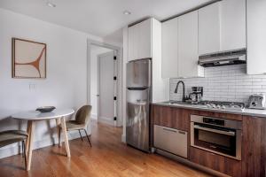 East Village 3br w elevator wd nr parks NYC-1209 في نيويورك: مطبخ مع طاولة وثلاجة حديد قابلة للصدأ