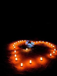a circle of candles with a woman in the middle at Wild Oryx Camp Bubbles in Wadi Rum