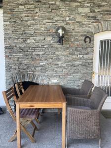 a wooden table and chairs in front of a stone wall at Haus Magnolia in Techelsberg am Worthersee