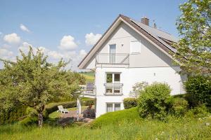 ein weißes Haus mit einem Balkon an der Seite in der Unterkunft Haus Ulla in Bad König