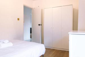 1 dormitorio con cama blanca y armario en Nice 4 Bedroom Apartment near City Centre 2-min Walk to Metro !! Business & Family Friendly!!, en Londres