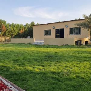 a house in a yard with a green field at مزرعة الفهد in Al Ḩazm