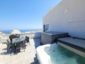 a balcony with a hot tub and a table and chairs at Prestigious & Modern SeaView Penthouse with Private Jacuzzi in Marsaskala