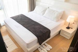 een wit bed met een zwarte deken en witte kussens bij Astra White Suite 12 in Chiang Mai